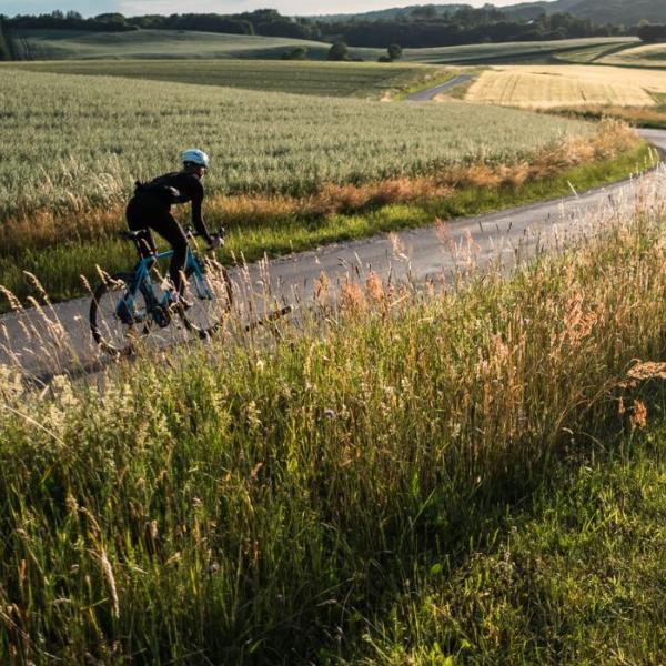 En person cykler på racercykel på landevejen langs åbne marker i Vejle