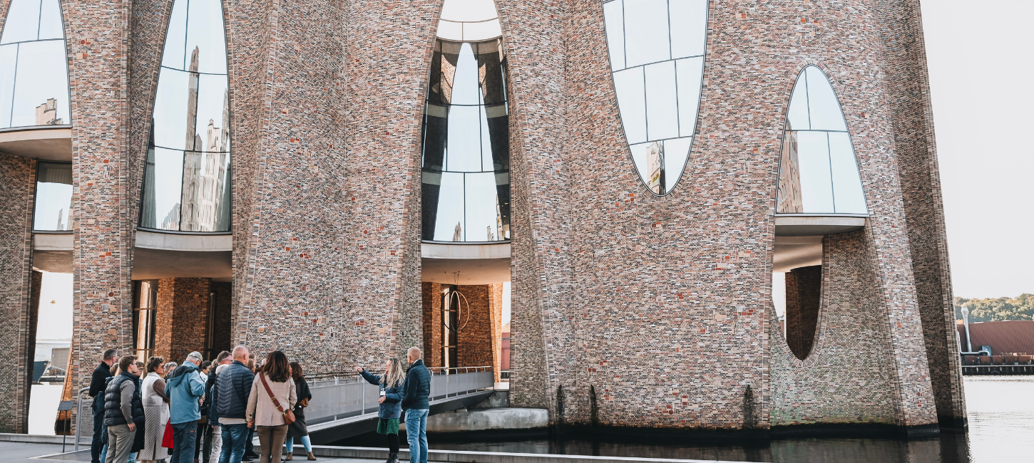 Rundvisning med VejleMuseernes guide ude foran Fjordenhus ved Vejle Fjord