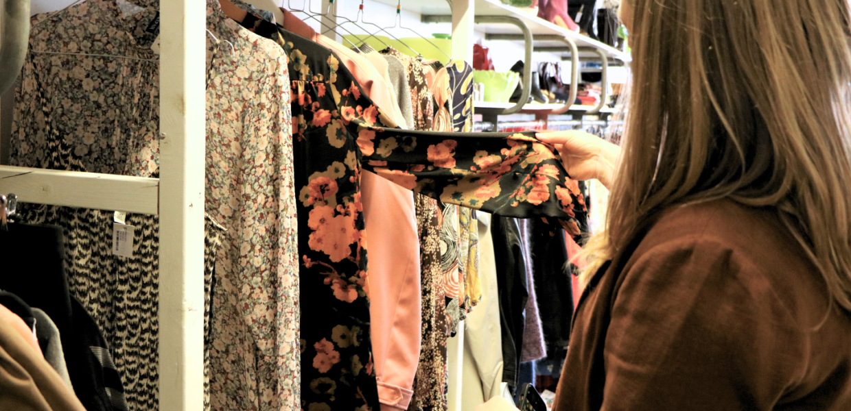 En person kigger på tøj i en genbrugsbutik i Give