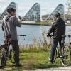 Tre cyklister cykler langs Østkystruten og holder pause ved Vejle Fjord og nyder udsigten til Bølgen