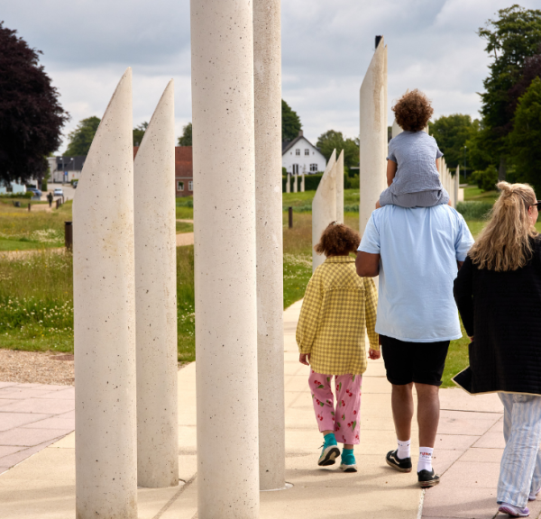En familie går tur i monumentområdet i Jelling ved palisaderne