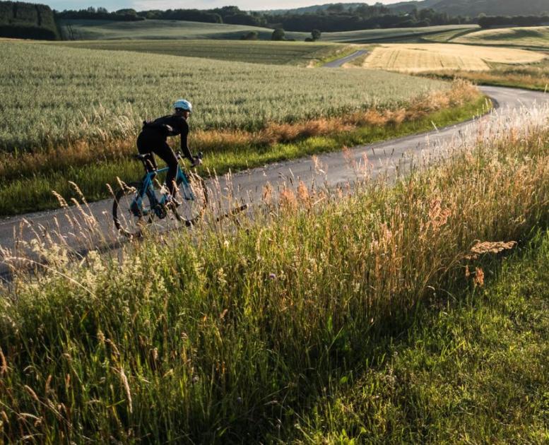 En person cykler på racercykel på landevejen langs åbne marker i Vejle