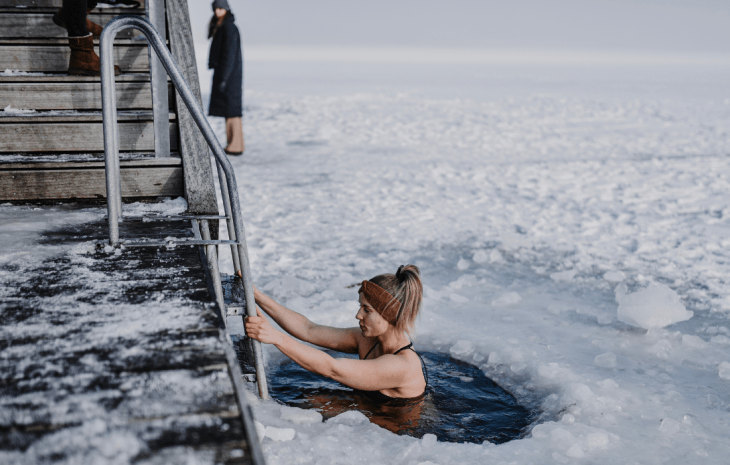 Kvinde der vinterbader ved fjorden under isen