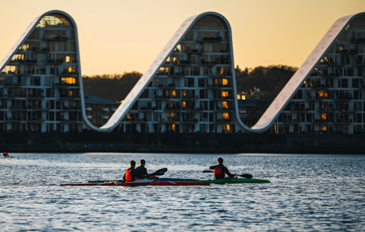 Folk i kajak på Vejle Fjord med Bølgen i baggrunden
